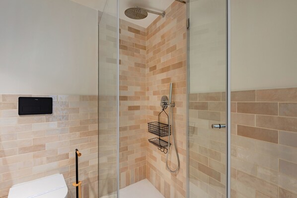 A modern bathroom with a glass-enclosed shower, a white toilet, and a towel rack.