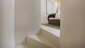 A minimalist staircase leading to a bedroom with a bed and a framed picture on the wall. - Urban Loft at Terracotta Collection (Porto)
