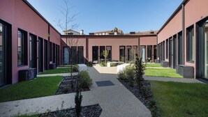 A modern building with a courtyard, featuring a central pathway, green spaces, and large windows. - Urban Loft at Terracotta Collection (Porto)