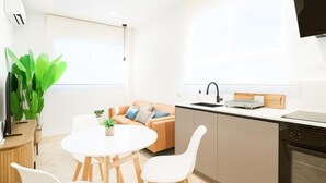 A modern kitchen with a dining area, a sofa, and a TV mounted on the wall. - Modern apartment 5 min from the beach (Puerto de Sagunto)