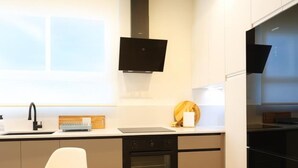 A modern kitchen with a built-in oven, a sink, and a small trash bin. - Modern apartment 5 min from the beach (Puerto de Sagunto)