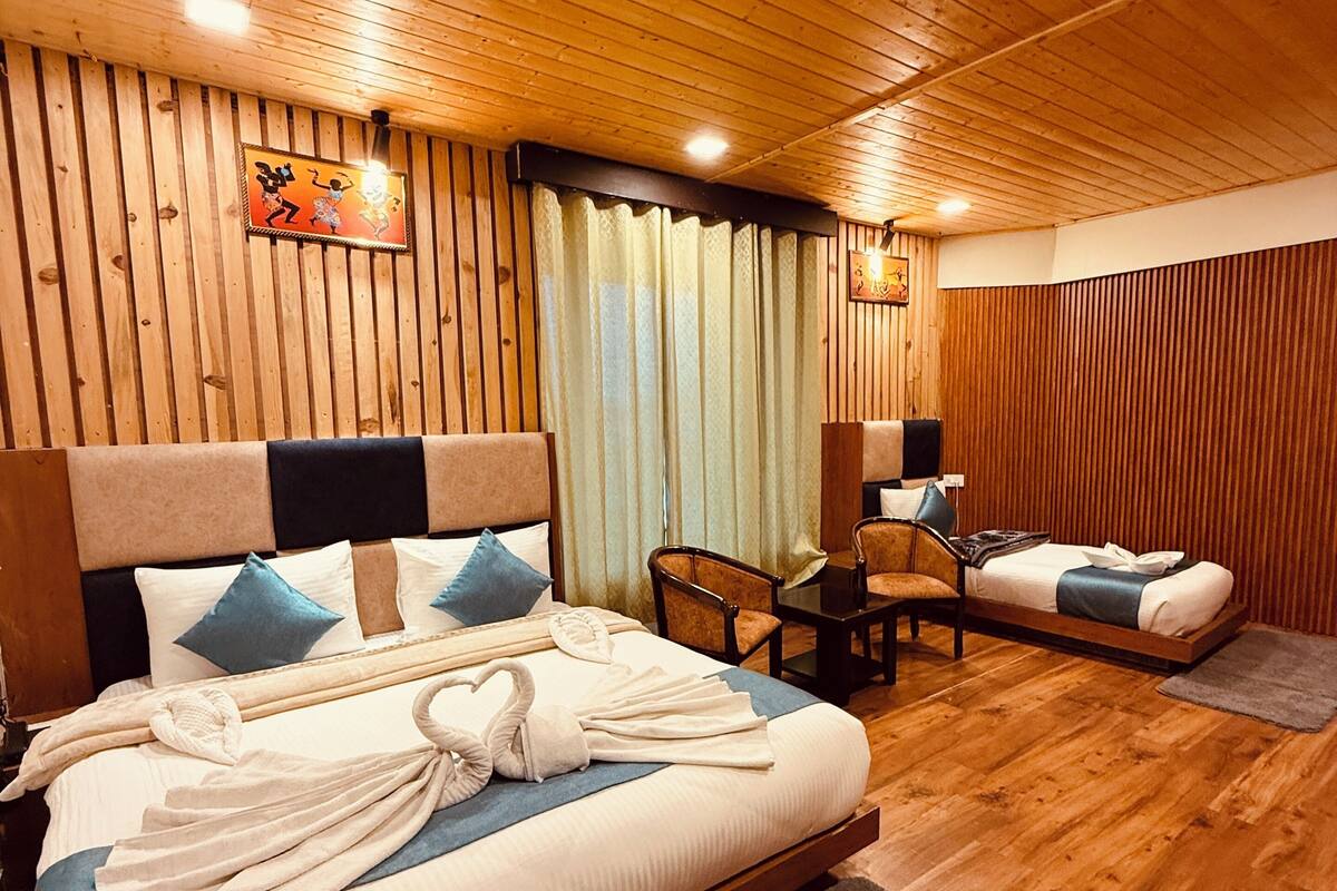 A hotel room with a wooden ceiling and walls, a large bed with a headboard, a desk, and a chair.