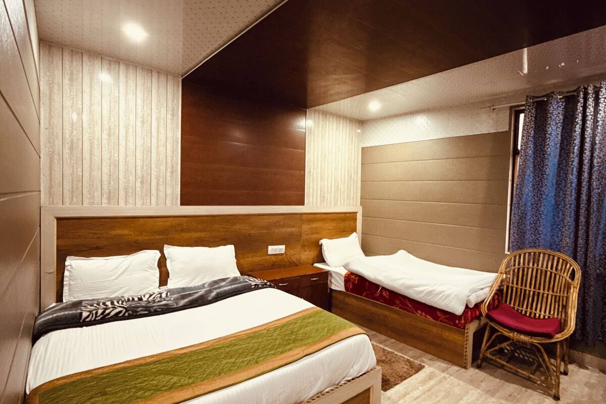 A modern hotel room with a large bed, a wooden headboard, a wicker chair, and a view of the city.