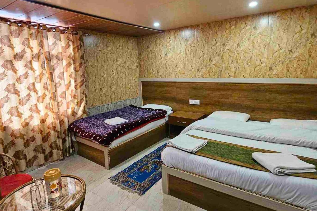 A hotel room with two beds, a small round table, and a chair.