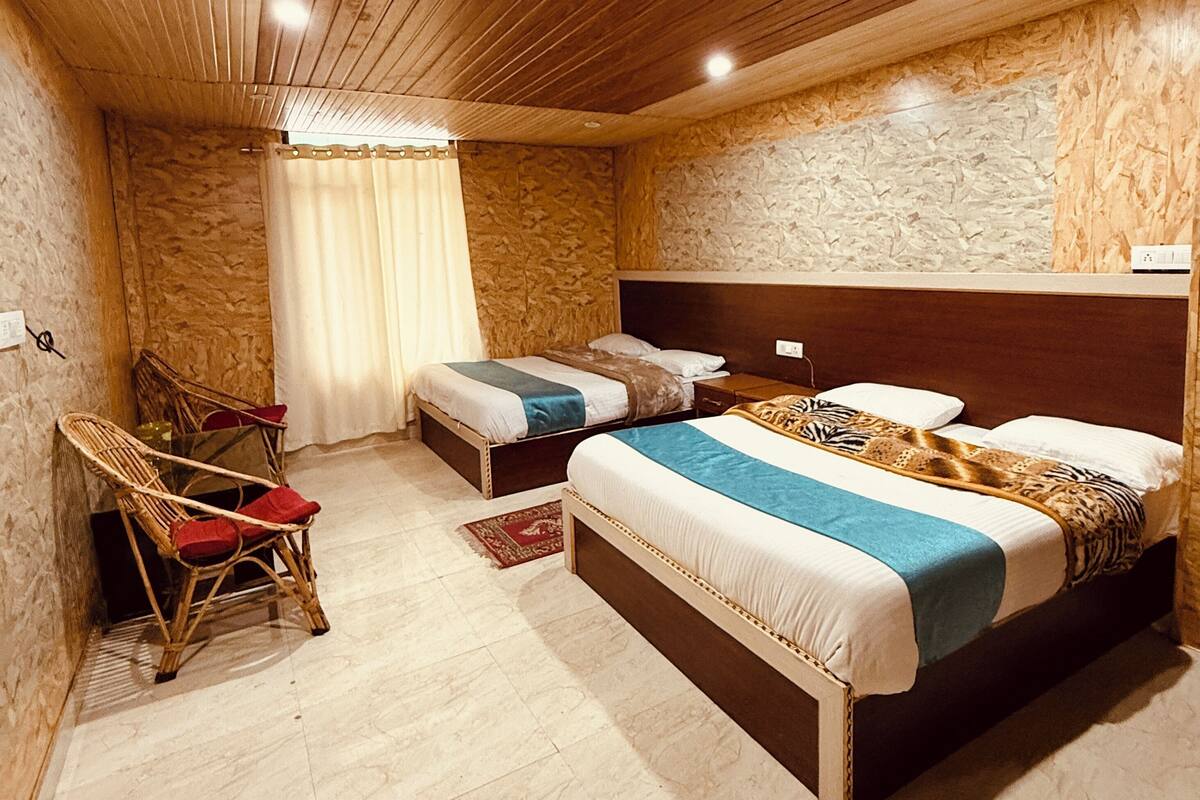 A bedroom with two single beds, a wooden ceiling, and a stone wall.