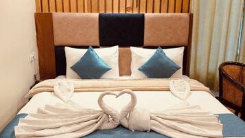 A neatly made bed with towels arranged in a heart shape, a wooden headboard, and a framed picture on the wall.