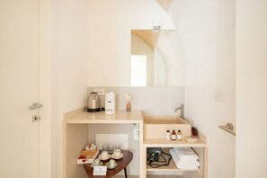 Une chambre d’hôtel compacte équipée d’une kitchenette, d’un évier et d’un miroir.