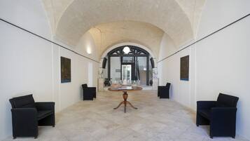 A spacious lobby with a high arched ceiling, a central round table, and black upholstered chairs.