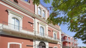 Un edificio de varios pisos con fachada roja, detalles blancos y balcones.