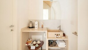 Una habitación de hotel compacta con kitchenette, un lavamanos y un espejo.