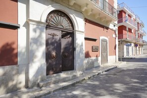 A building with a large, ornate entrance door, a small balcony, and a clear sky.