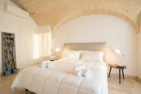 Une chambre d’hôtel avec un grand lit, une tête de lit, une table de chevet avec une lampe et un climatiseur fixé au mur.