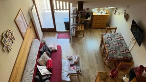 A cozy living room with a sofa, a dining table, and a kitchen area. - Cozy studio 5 pers. at the slopes (Saint-François-Longchamp)