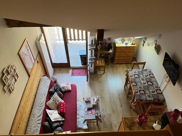 A cozy living room with a sofa, a dining table, and a kitchen area.