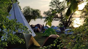 A campsite with multiple tents near a lake, surrounded by trees.