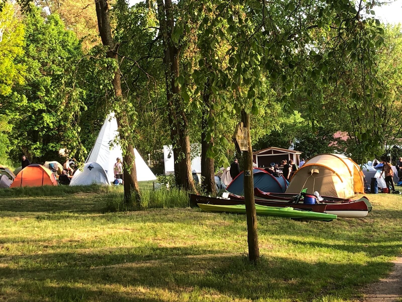 Un terrain de camping avec plusieurs tentes et un canoë.