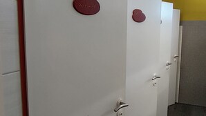 A row of white doors with red handles and a red plaque on each door.