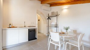 A modern kitchen with a dishwasher, a dining area with a round table and chairs, and a wooden ceiling.