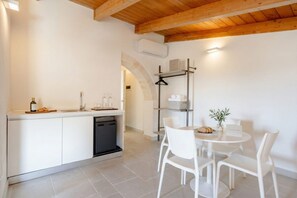 A modern kitchen with a dishwasher, a dining area with a round table and chairs, and a wooden ceiling.