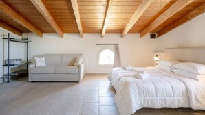 A bedroom with a wooden ceiling, a bed, a sofa, a window, and a wall-mounted shelf.