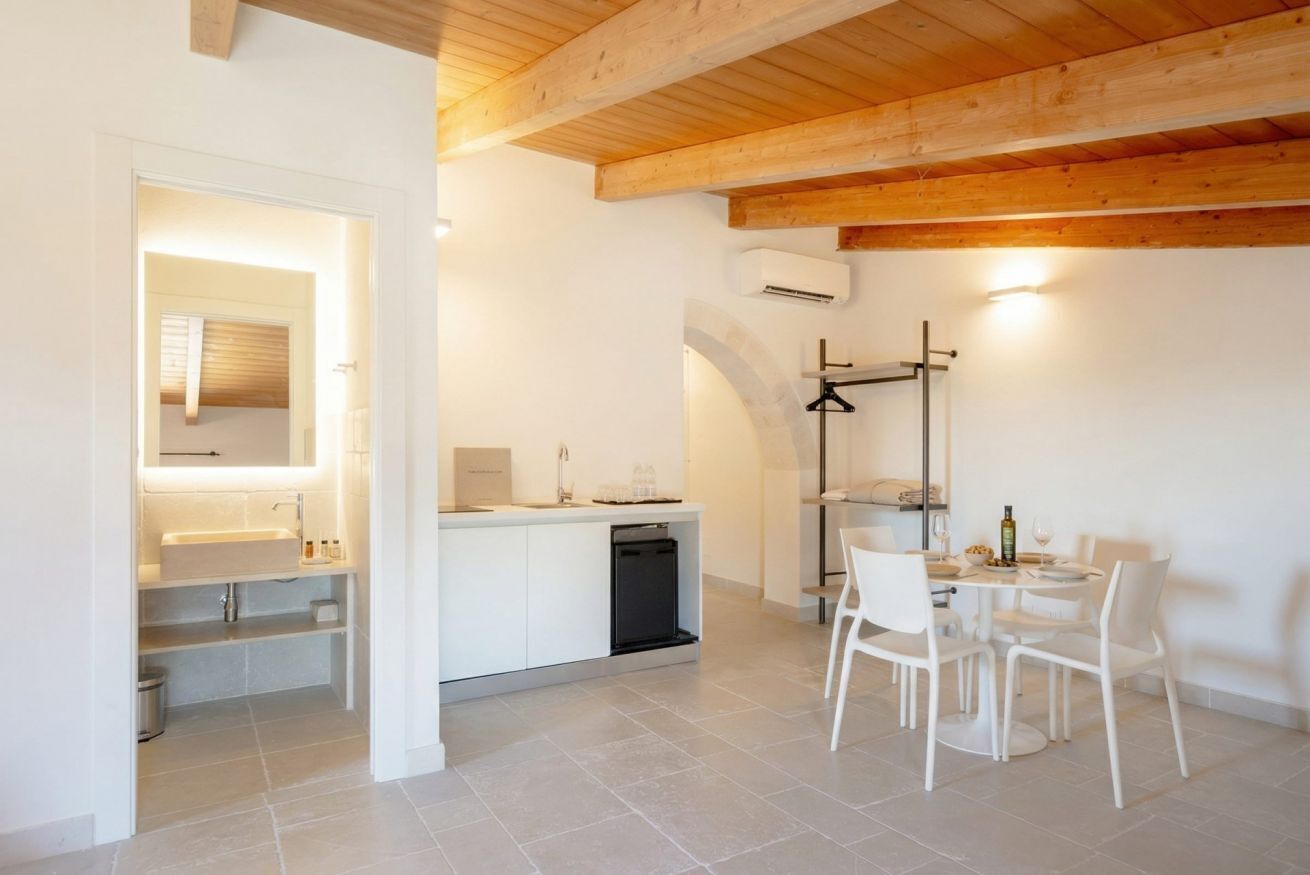 Una cucina moderna con mobili bianchi, lavastoviglie integrata e un'area pranzo con sedie e tavolo bianchi.