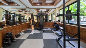 Un gimnasio con equipo de ejercicio, un espejo y una ventana con vista a zonas verdes.