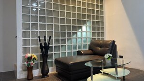 Una sala de estar moderna con un separador de vidrio, un sofá de cuero, una mesa de centro de vidrio y un jarrón con flores.