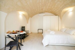 A room with a bed, a table with food, a chair, and a TV.