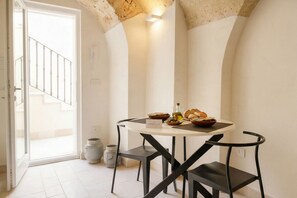 A dining area with a round table, black chairs, and a view of a staircase.