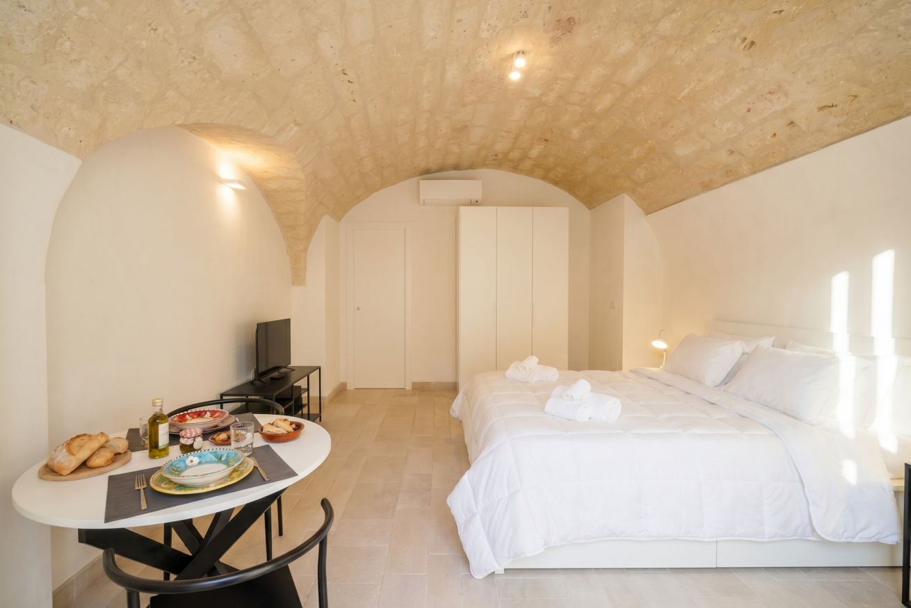 Una camera da letto con un letto, un tavolo con prodotti per la colazione, una TV e un soffitto a volta.