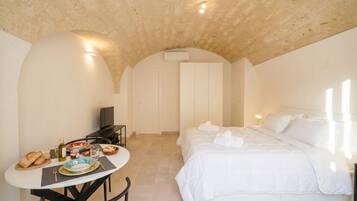 Una camera da letto con un letto, un tavolo con prodotti per la colazione, una TV e un soffitto a volta.
