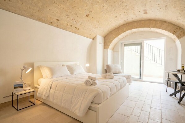 A bedroom with a large bed, a desk, and a chair.