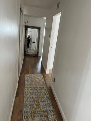 A hallway with wooden flooring and a patterned rug, leading to a door at the end. - Costal Cottage -boddam-sleeps6- Pet Friendly (Peterhead)
