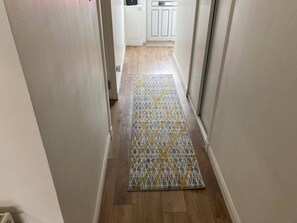 A hallway with a patterned rug, wooden flooring, and white cabinets. - Costal Cottage -boddam-sleeps6- Pet Friendly (Peterhead)