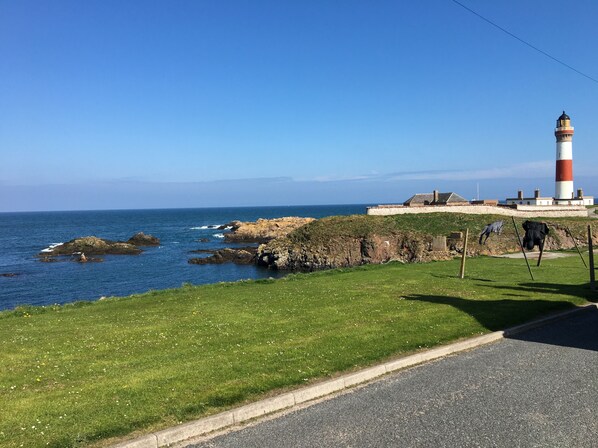 A coastal view with a lighthouse, grassy area, and rocky shoreline. - Costal Cottage -boddam-sleeps6- Pet Friendly (Peterhead)
