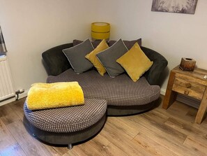 A modern living room with a sectional sofa, a yellow pouf, and a wooden side table. - Costal Cottage -boddam-sleeps6- Pet Friendly (Peterhead)