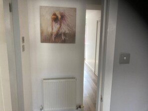 A hallway with a radiator, a painting on the wall, and a door leading to another room. - Costal Cottage -boddam-sleeps6- Pet Friendly (Peterhead)