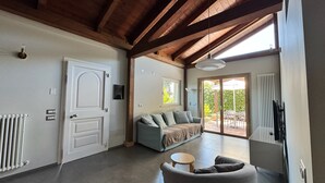 A spacious room with a wooden ceiling, a sofa, a small table, and a sliding glass door leading to an outdoor area. - ChaletSoleLuna sea view, Italian Villa, Riccione Misano, Pet Friendly! (Emilia-Romagna)