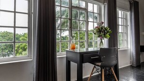 Une pièce comprenant un bureau, deux chaises, un vase avec des fleurs et un verre contenant un liquide orange.