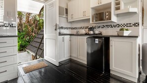 Une cuisine moderne avec des meubles blancs, un réfrigérateur noir et un pare-feu en carreaux.