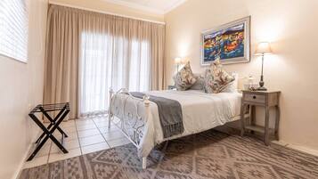 A hotel room with a bed, a nightstand, a lamp, a painting, and a window with curtains.