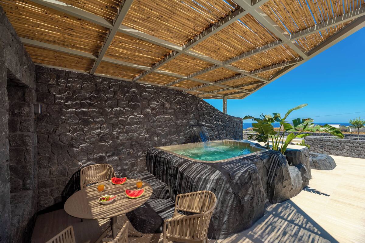 A stone wall, a hot tub, and a table with chairs.