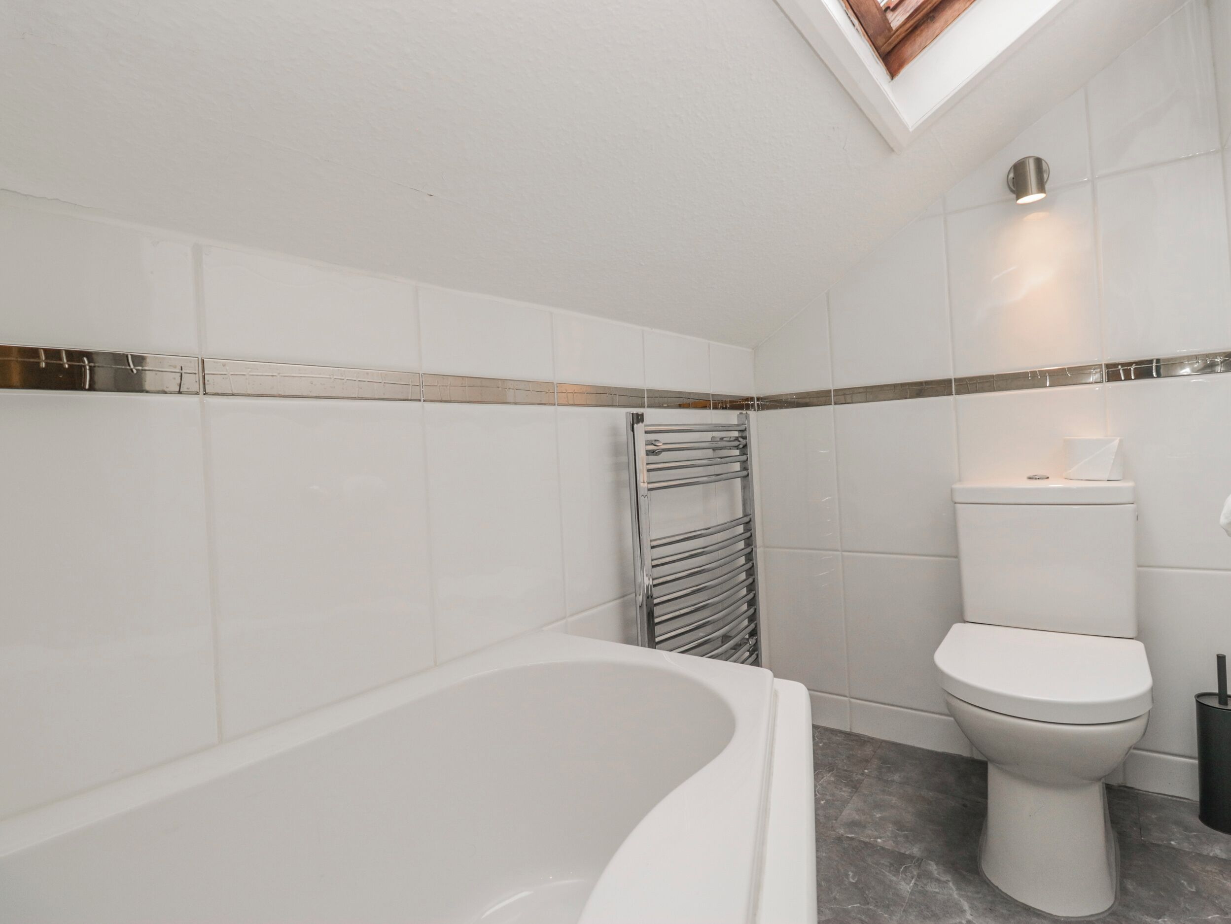 A modern bathroom with a freestanding bathtub, a toilet, and a towel rack.