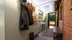 A narrow hallway with a glass ceiling, a wooden bench, and a small table. - The Alms House East (Gloucester)