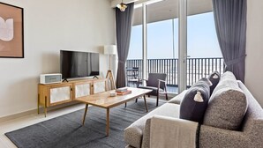 A modern living room with a sofa, a coffee table, a TV, and a balcony with a view.