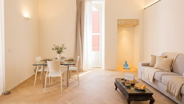 Ein modernes Wohnzimmer mit einem Glastisch, weißen Stühlen, einer Couch und einem Couchtisch.
