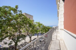 Ein Balkon mit Blick auf eine von Bäumen gesäumte Straße und ein Gebäude im Hintergrund.