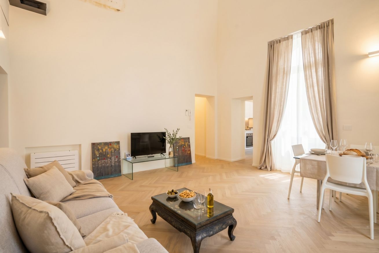 A living room with a sofa, a coffee table with snacks, a TV, and a dining area with chairs and a table.