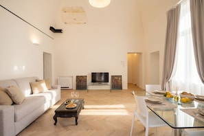 Un salon moderne comprenant un canapé, une table basse, un téléviseur et un coin repas avec une table et des chaises en verre.