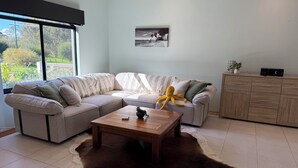 A modern living room with a sectional sofa, a wooden coffee table, a cowhide rug, and a view of greenery outside. - Waterlink Retreat - canal views with easy access to both the canal and the river (South Yunderup)